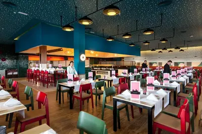 a restaurant with white tables and red chairs at Hotel Riu Chiclana - All Inclusive in Chiclana de la Frontera