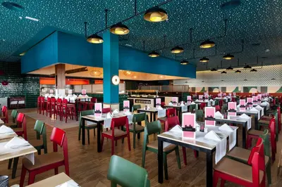 a dining room with tables and red chairs at Hotel Riu Chiclana - All Inclusive in Chiclana de la Frontera