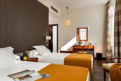 a hotel room with two beds and a desk at Hotel de Francia y París in Cádiz