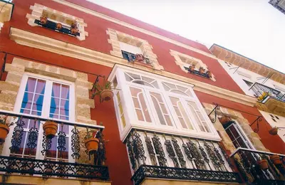 a red building with white windows and balconies at Dormir en Cádiz in Cádiz