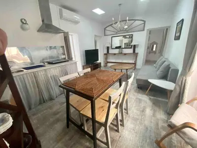 a dining room and living room with a table and chairs at Anticuario en el Teatro Falla in Cádiz