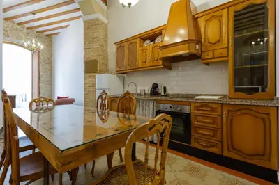 a kitchen with wooden cabinets and a table and chairs at Casa Del COLECCIONISTA by Cadiz4Rentals in Cádiz