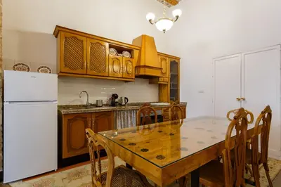 a kitchen with a wooden table and a white refrigerator at Casa Del COLECCIONISTA by Cadiz4Rentals in Cádiz