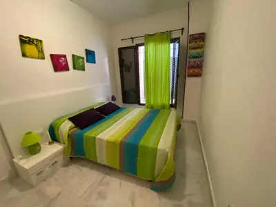 a bedroom with a bed with a colorful striped blanket at APARTAMENTO Centro ciudad in Jerez de la Frontera