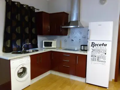 a kitchen with a washer and a white refrigerator at NOVO Apartahotel & Restaurante in Las Cabezas de San Juan