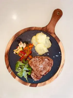 a plate of food with meat and vegetables on a table at NOVO Apartahotel & Restaurante in Las Cabezas de San Juan