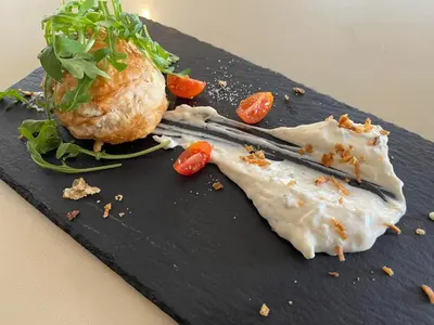 a black plate with a sandwich and vegetables on it at NOVO Apartahotel & Restaurante in Las Cabezas de San Juan