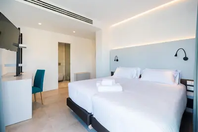 a bedroom with a large white bed and a television at Dormos Hotel in Cádiz