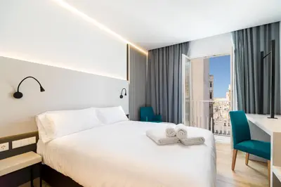 a hotel room with a bed and a desk and a window at Dormos Hotel in Cádiz