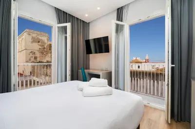 a bedroom with a large bed and a large window at Dormos Hotel in Cádiz