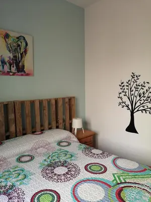a bedroom with a bed with a tree on the wall at Corazón del Puerto de Santa María in El Puerto de Santa María