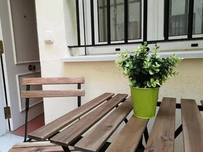 a wooden bench with a potted plant sitting next to a window at Corazón del Puerto de Santa María in El Puerto de Santa María