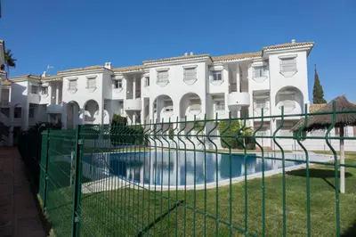 a fence in front of a building with a pool at Apartamento Alextia La Barrosa in Chiclana de la Frontera