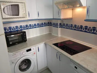 a kitchen with a washing machine and a microwave at Apartamento Alextia La Barrosa in Chiclana de la Frontera