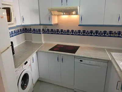 a kitchen with white cabinets and a washer and dryer at Apartamento Alextia La Barrosa in Chiclana de la Frontera