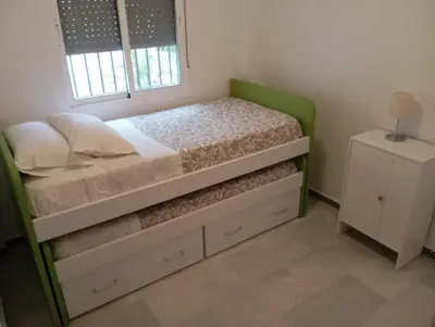 a bedroom with a green bed with a window at Apartamento Alextia La Barrosa in Chiclana de la Frontera