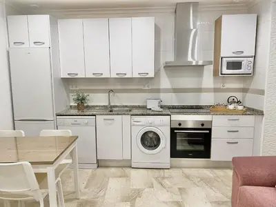 a kitchen with white cabinets and a washing machine at San Francisco 15 in Cádiz