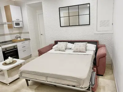 a small bedroom with a bed and a kitchen at San Francisco 15 in Cádiz