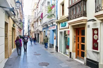 a group of people walking down a street with buildings at San Francisco 15 in Cádiz