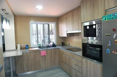 a kitchen with wooden cabinets and a stainless steel refrigerator at Relax y playa en la Barrosa in Chiclana de la Frontera