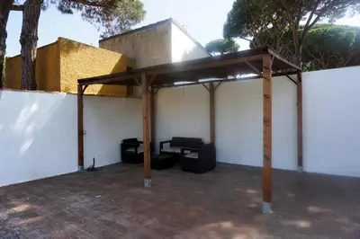 a pavilion with a table and a chair under it at Relax y playa en la Barrosa in Chiclana de la Frontera