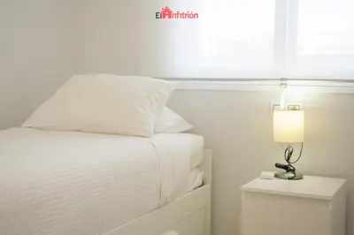 a bedroom with a bed with a lamp on a night stand at ATICO NUEVO en el BARRIO ALTO SANLÚCAR in Sanlúcar de Barrameda