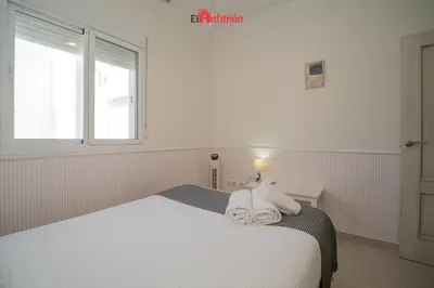 a white bed in a room with a window at ATICO NUEVO en el BARRIO ALTO SANLÚCAR in Sanlúcar de Barrameda