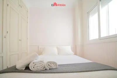 a white bedroom with a bed with towels on it at ATICO NUEVO en el BARRIO ALTO SANLÚCAR in Sanlúcar de Barrameda