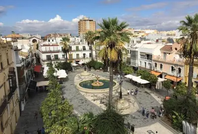 a city with a fountain and palm trees and buildings at Almijar 9 in Sanlúcar de Barrameda