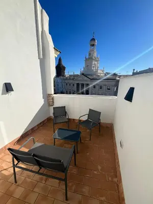 a balcony with chairs and tables and a building at Penthouse La plaza en Cádiz Centro Grupo AC Gestion in Cádiz
