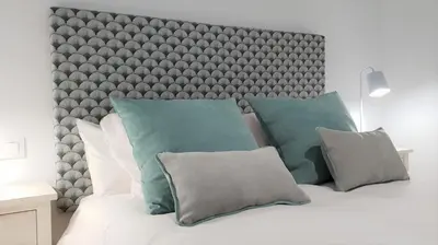 a bedroom with a large bed with green and grey pillows at Casa Velero 32 in Sanlúcar de Barrameda