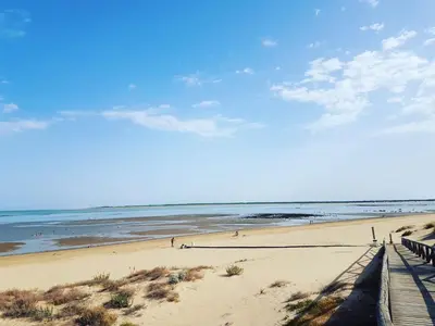 a beach with people walking on the sand at Casa Velero 32 in Sanlúcar de Barrameda