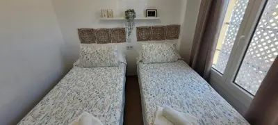 two beds in a small room with a window at APARTAMENTOs IGLESIA DE SANTIAGO in Jerez de la Frontera