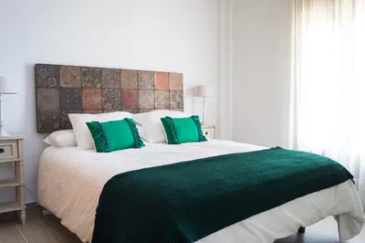 a bedroom with a large bed with green pillows at Casa de la Jara 10 in Sanlúcar de Barrameda