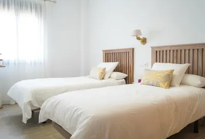 a bedroom with two beds with white sheets and a window at Casa de la Jara 10 in Sanlúcar de Barrameda