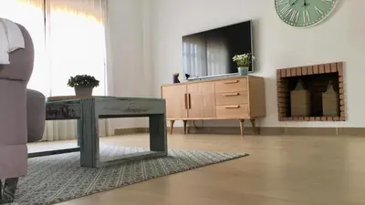 a living room with a table and a dresser and a clock at Casa de la Jara 10 in Sanlúcar de Barrameda