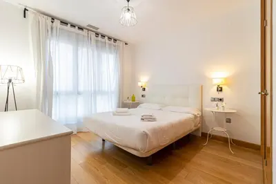 a white bedroom with a bed and a window at Allo Apartments Valdespino Parking Centro 2 Habitaciones in Jerez de la Frontera