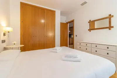 a bedroom with a white bed and a wooden cabinet at Allo Apartments Valdespino Parking Centro 2 Habitaciones in Jerez de la Frontera