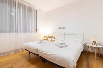 a white bedroom with a bed and a window at Allo Apartments Valdespino Parking Centro 2 Habitaciones in Jerez de la Frontera