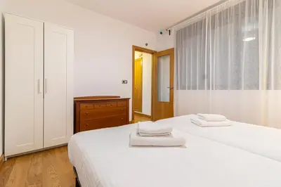 a white bedroom with two beds and a window at Allo Apartments Valdespino Parking Centro 2 Habitaciones in Jerez de la Frontera