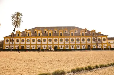 a large yellow building with a palm tree in front of it at Allo Apartments Valdespino Parking Centro 2 Habitaciones in Jerez de la Frontera