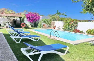 a swimming pool with two blue lounge chairs next to it at Chalet la Dehesa in Conil de la Frontera