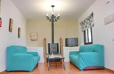 a living room with two blue chairs and a tv at Chalet la Dehesa in Conil de la Frontera