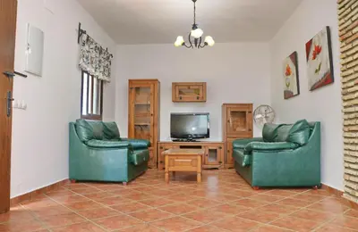 a living room with two green chairs and a television at Chalet Dehesa Villa in Conil de la Frontera