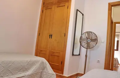 a bedroom with a wooden cabinet and a fan at Chalet Dehesa Villa in Conil de la Frontera