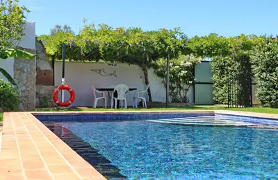 a swimming pool with a table and chairs next to a house at Chalet Dehesa Villa in Conil de la Frontera
