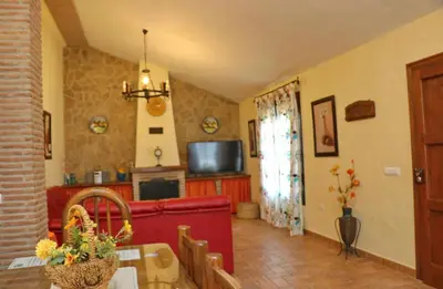 a living room with a red couch and a television at Chalet de la casa Forestal in Conil de la Frontera