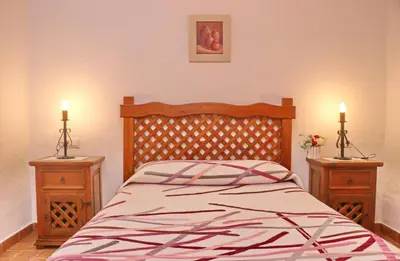 a bedroom with a bed with two night stands and two candles at Chalet de la casa Forestal in Conil de la Frontera