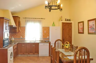 a kitchen with a table and chairs and a refrigerator at Chalet de la casa Forestal in Conil de la Frontera
