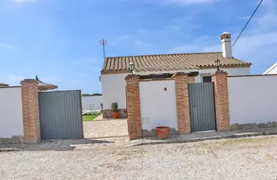 a brick house with two white garage doors at Chalet de la casa Forestal in Conil de la Frontera